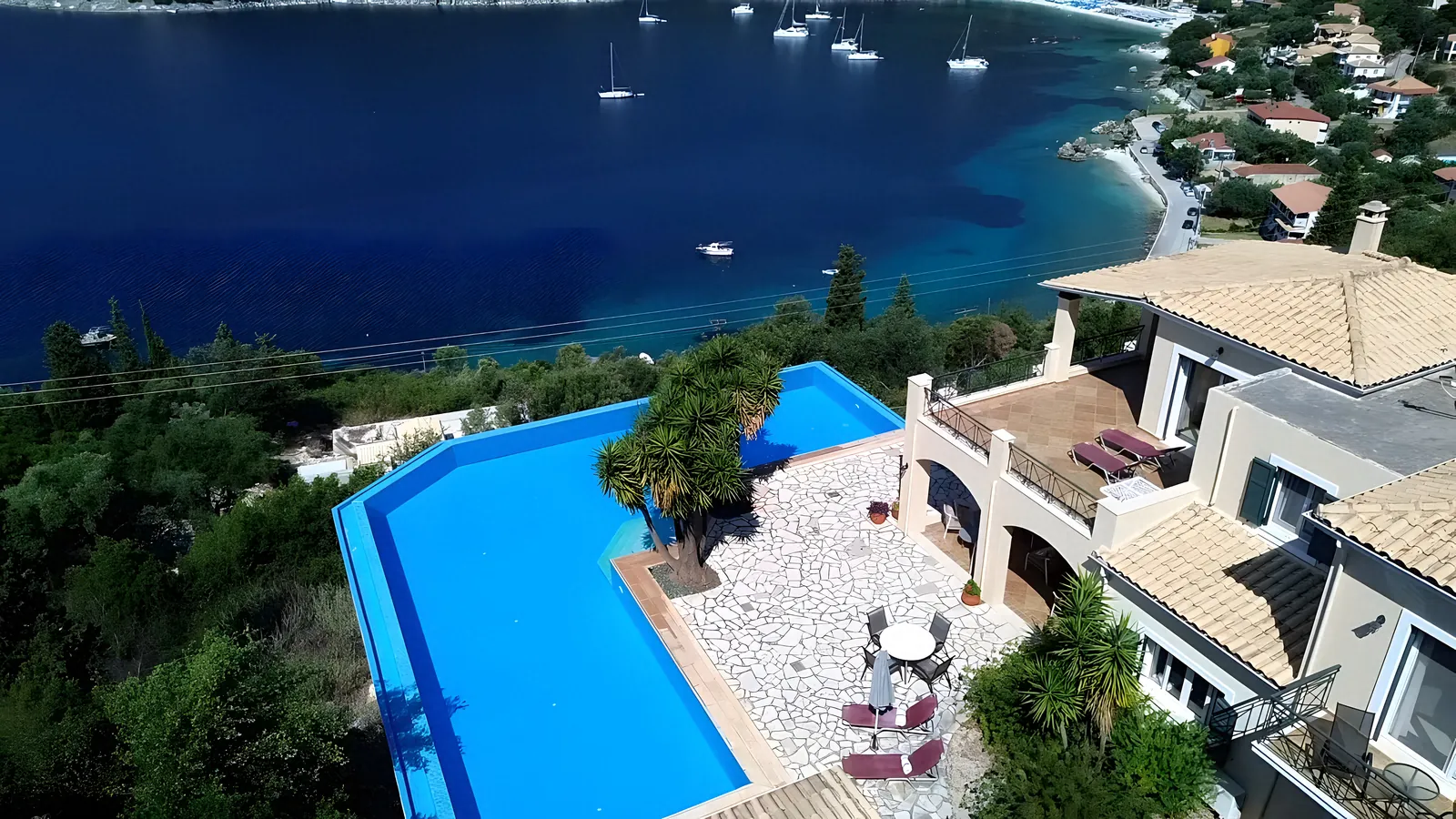 The L-shaped pool and the house from the air, with the bay below